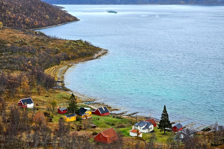 Scenic view of colorful houses by a lake with a mountainous backdrop.