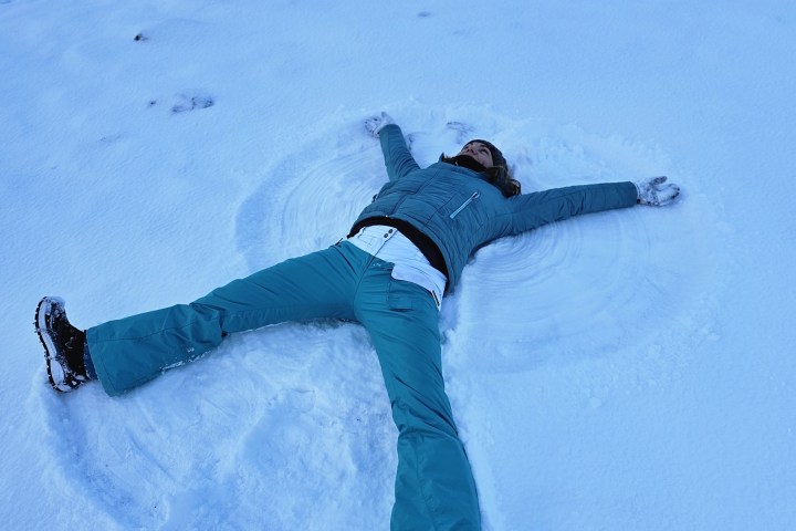 Person making a snow angel in a snowy area.